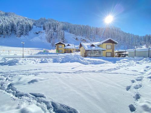 a snow covered yard with a house in the background at Arco Hotels & Resorts sonamarg in Sonāmarg
