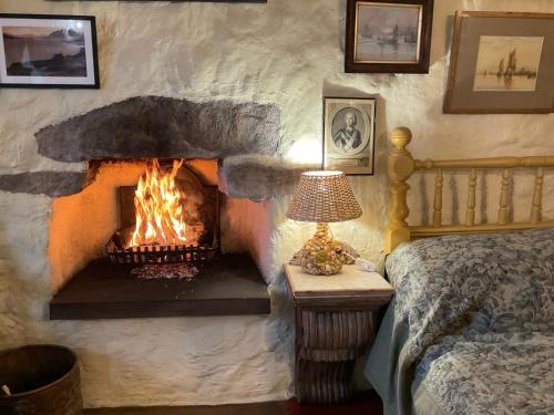 a stone fireplace in a bedroom with a bed and a lamp at The Cottar in Broadford