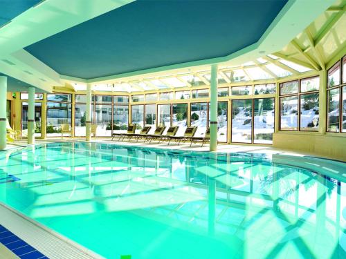 a large swimming pool with chairs in a building at Landhotel Zenzerwirt in Hippach
