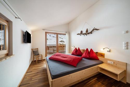 Habitación con cama con almohadas rojas. en Seppnerhof Ferienwohnung Edelweiss, en Pfelders