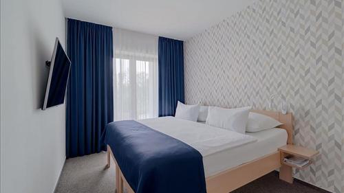 a bedroom with a bed and a window with blue curtains at HOTEL Hraniční zámeček in Hlohovec