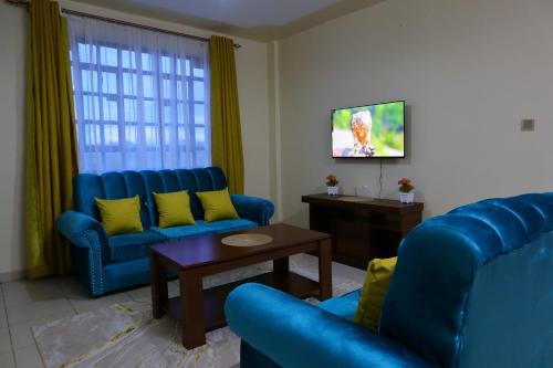 a living room with two blue chairs and a table at Gazena homes in Thika