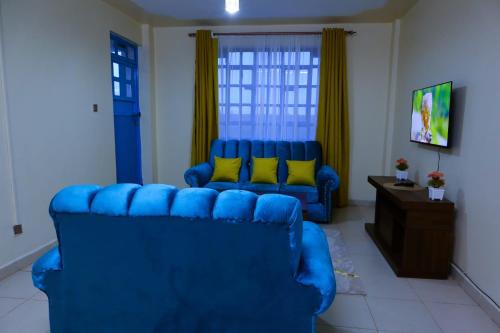 sala de estar con sofá azul y almohadas amarillas en Gazena homes, en Thika