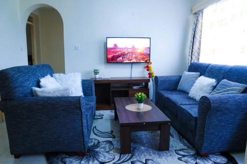 a living room with two blue couches and a table at Gazena homes in Thika