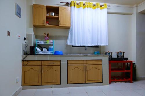 a kitchen with wooden cabinets and a white curtain at Gazena homes in Thika