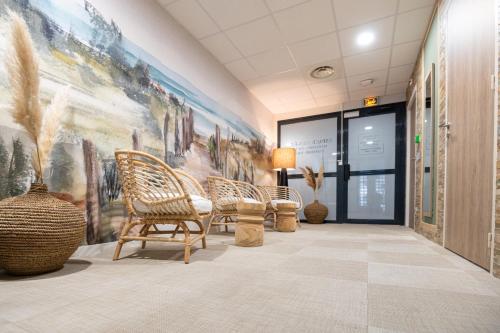 a lobby with chairs and a large painting on the wall at Kyriad Prestige Residence & Spa Cabourg-Dives-sur-Mer in Dives-sur-Mer