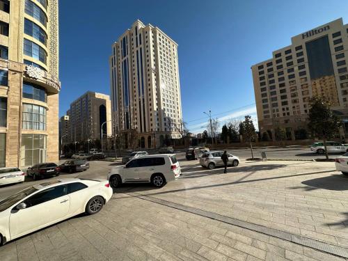 a parking lot with cars in a city with tall buildings at IsraHotel Dushanbe in Dushanbe