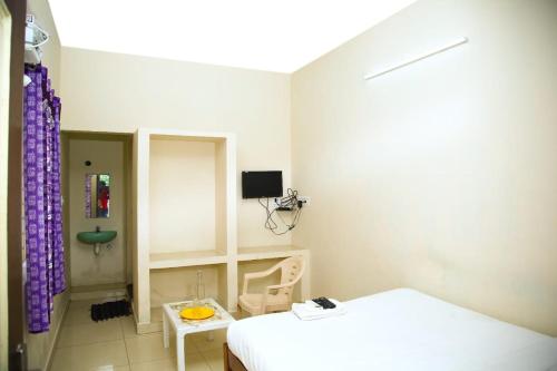 a white room with a bed and a tv at ‌‌Florence guest house in Puducherry