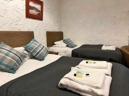 two beds in a hotel room with towels on them at Black Dog Inn in Bolton