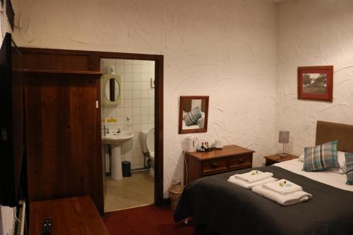 a bedroom with a bed and a bathroom with a sink at Black Dog Inn in Bolton