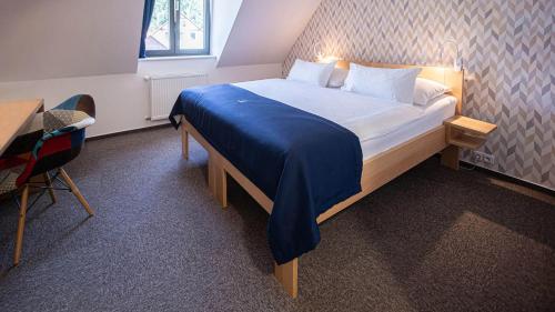 a bedroom with a bed with a blue blanket on it at HOTEL Hraniční zámeček in Hlohovec