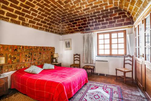 a bedroom with a red bed and a brick wall at Casa do Mar in Sesimbra