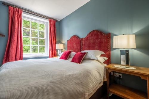 a bedroom with a large bed with red curtains and a window at The East Wing BB in Wymondham