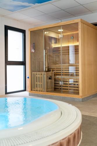 a large swimming pool with a tub in a room at Kyriad Prestige Residence & Spa Cabourg-Dives-sur-Mer in Dives-sur-Mer