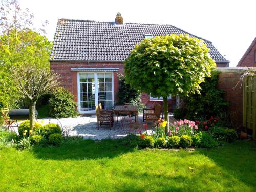 un jardin avec une table, des chaises et des fleurs dans l'établissement Campen Cottage, à Krummhörn