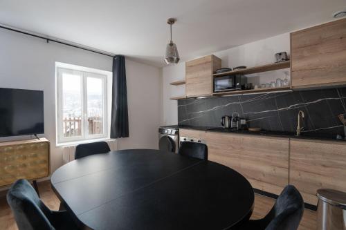 a dining room with a black table and chairs at K1, appartement avec grande terrasse et vue pistes in Gérardmer