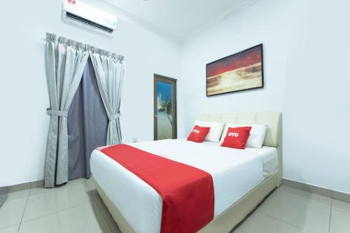 una camera da letto con un grande letto bianco con cuscini rossi di Sg Rengit City Resort 1 a Kampung Sungai Rengit
