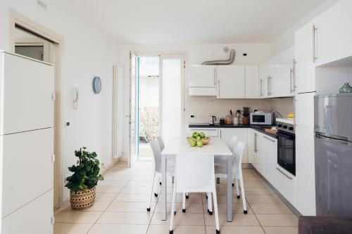 a kitchen with white cabinets and a white table and chairs at ANIMA JESOLO - DRAGO VILLAGE, Beach & Pool, 2 Parkings in Lido di Jesolo