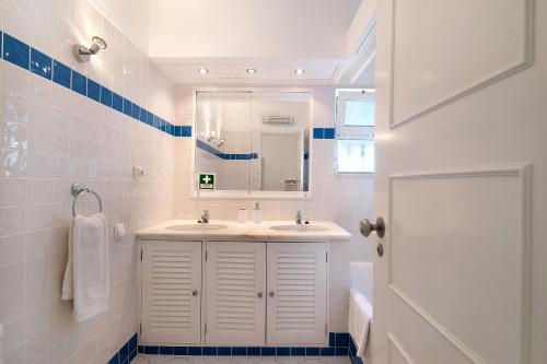 een witte badkamer met een wastafel en een spiegel bij Bia in Almancil