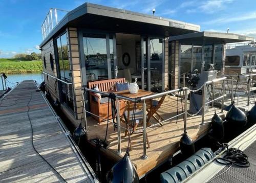 a house boat with a table on a dock at Huisboot Comfort M Plus Limburg in Kinrooi
