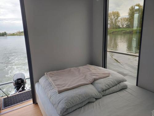 a bed in a room next to a window at Huisboot Comfort M Plus Limburg in Kinrooi