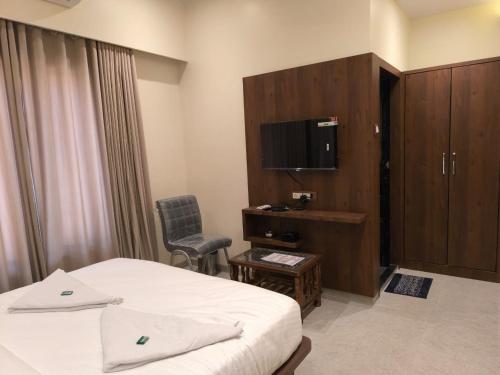 um quarto de hotel com uma cama e uma televisão em Sharan Residency em Nova Bombaim