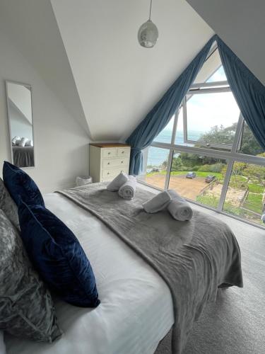 ein Schlafzimmer mit einem Bett mit Kissen und einem großen Fenster in der Unterkunft BayVue Apartment & Apartment 7, The Bay House in Shanklin