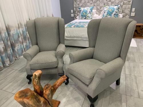 two chairs and a table in a bedroom with a bed at Ecolux in Marracuene