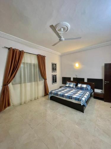 Schlafzimmer mit einem Bett und einem Deckenventilator in der Unterkunft Timba ciné01 in Cotonou