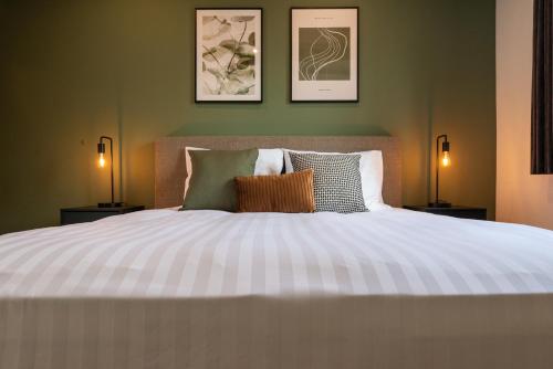 a bedroom with a large white bed with two lamps at Hotel De Hoogmolen in Oudsbergen 