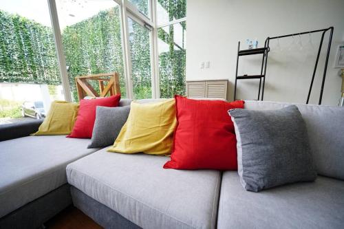 a couch with many colorful pillows on it at ⁂ビーチからすぐ！開放的な一軒家で家族や友人と湘南を満喫！新江ノ島水族館まで徒歩で約6分⁂ in Katase