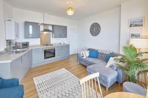 a living room with a blue couch and a kitchen at Luxury 2 Bedroom Fully Loaded Apartment in Redcar