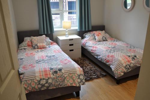 a bedroom with two beds and a lamp and a window at Goldfinch Lodge in Droitwich