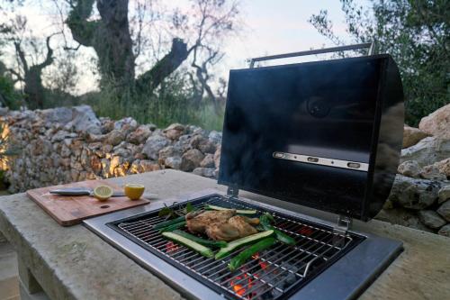 a chicken cooking on a grill with vegetables on it at Il Cubetto- a cute mini house in olive grove in Surano