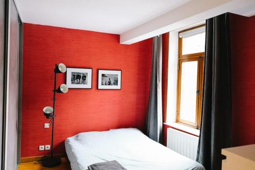 Cette chambre rouge comprend un lit et une fenêtre. dans l'établissement Magnifique duplex de 90m² au coeur de Lille, à Lille