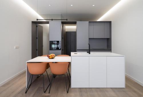 a kitchen with white cabinets and a table and chairs at Cosy Loft's Valencia in Catarroja