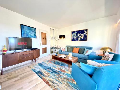 un salon avec un canapé bleu et une télévision dans l'établissement Le Verdi By SCLS Locations, à Cannes