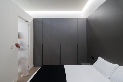 sypialnia z czarno-białym łóżkiem i osoba stojąca w drzwiach w obiekcie Cosy Loft's Valencia w mieście Catarroja