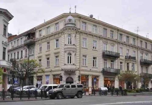 a large white building with cars parked in front of it at Rooftop Apartments at Rustaveli Avenue in Tbilisi City