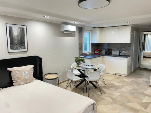 a bedroom with a bed and a table and a kitchen at STUDIO SUR LA PROMENADE DES ANGLAIS AVEC VUE MER ORIGINALE À 40 m DE LA PLAGE in Nice