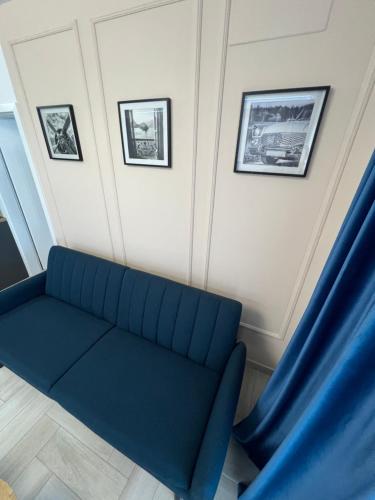 a blue couch in a room with pictures on the wall at Sunny Apartments Avanera Suceava in Suceava