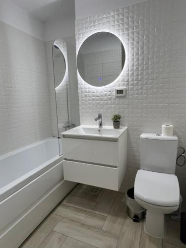 ein Badezimmer mit einem Waschbecken, einem WC und einem Spiegel in der Unterkunft Sunny Apartments Avanera Suceava in Suceava