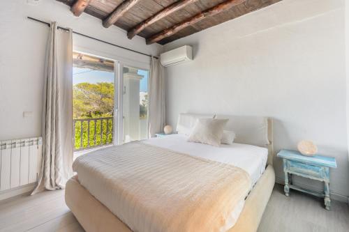 a white bedroom with a bed and a window at Cala Salada Sunset View in San Antonio