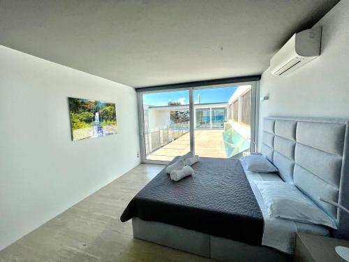 ein Schlafzimmer mit einem Bett und einem großen Fenster in der Unterkunft Seafront Villa Sunset Alcudia in Alcúdia
