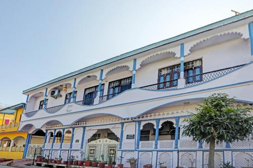 um edifício branco e azul com uma árvore em frente em OYO 82032 The Gunjan Villa Palace em Udaipur