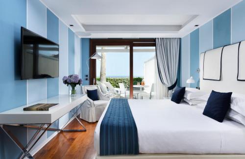 a bedroom with a white bed and blue walls at La Plage Resort in Taormina