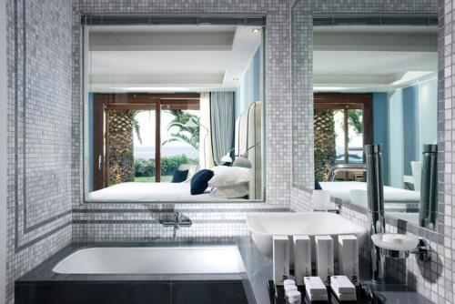 a bathroom with a tub and a large mirror at La Plage Resort in Taormina