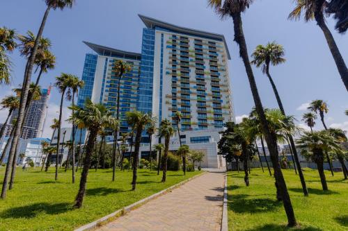 una pasarela con palmeras frente a un edificio alto en Bellevue Residence Suites en Batumi
