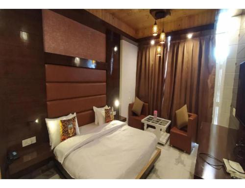 a bedroom with a bed and two chairs in it at Hotel Atithi, Near Yes Bank, Mall Road, Mussoorie in Mussoorie