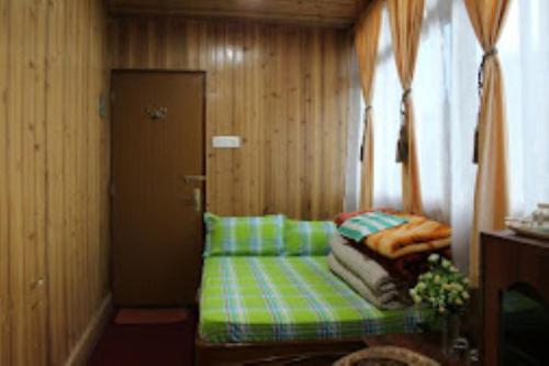 een kleine kamer met een groene bank en een deur bij Darjeeling Inn , Darjeeling in Darjeeling